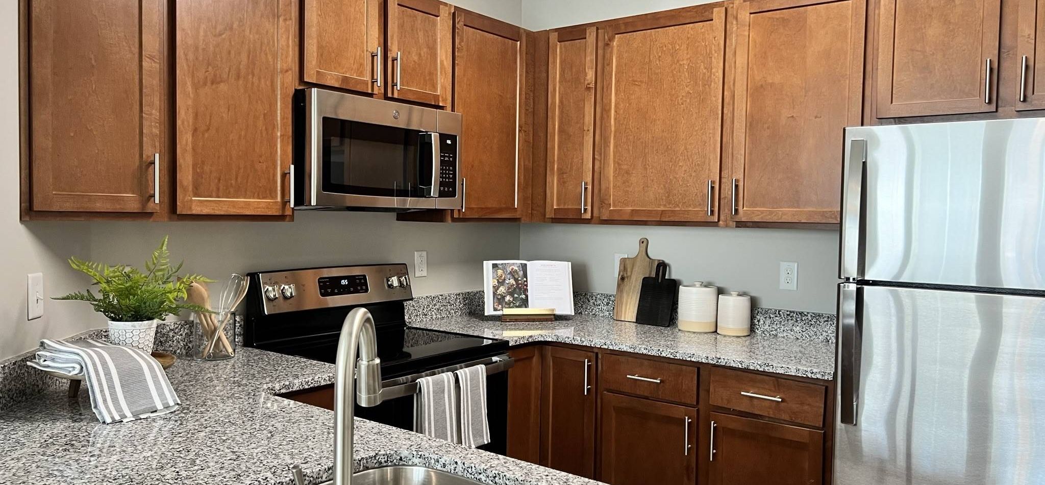 Modern kitchen with granite countertops and stainless steel appliances at Hawthorne at Stillwater, epitomizing luxury apartment living in Sneads Ferry, NC.